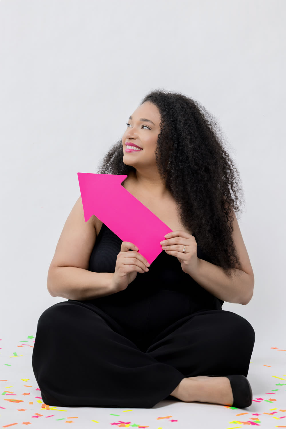 Jillian sitting on the floor holding a pink arrow